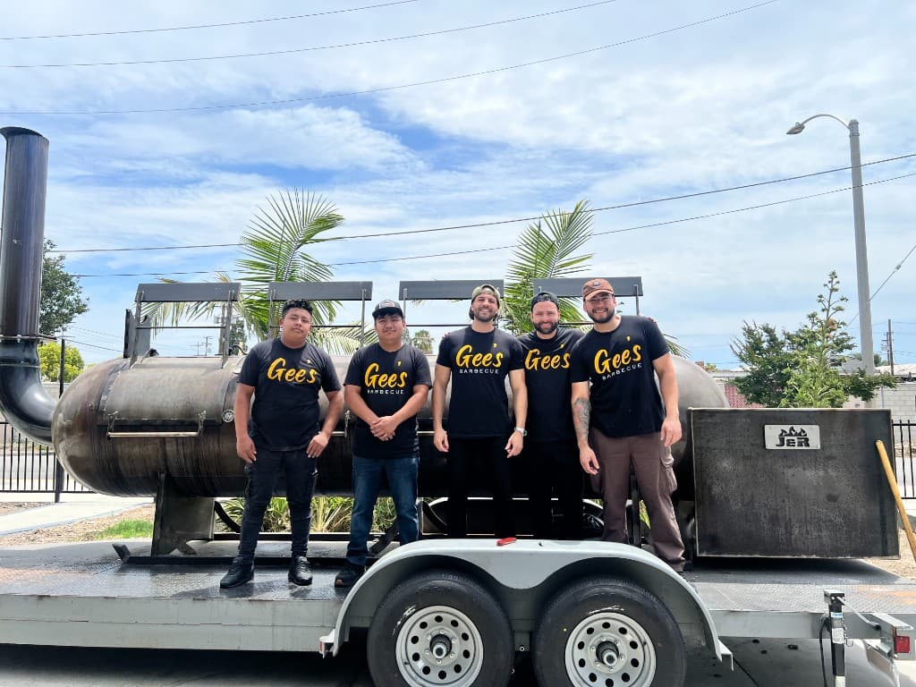 The Gee's BBQ team standing in front of their trailer-mounted smoker